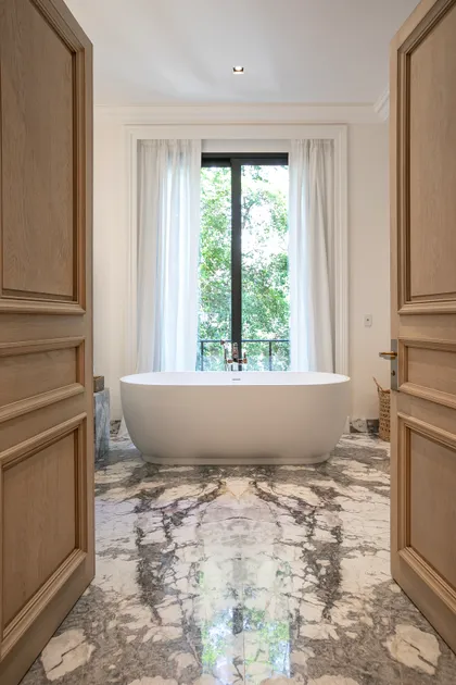 Baño moderno con bañera exenta, mármol y grandes ventanales — proyecto OBRA RECOLETA, por Estudio Xime Fontan Balestra, en Recoleta